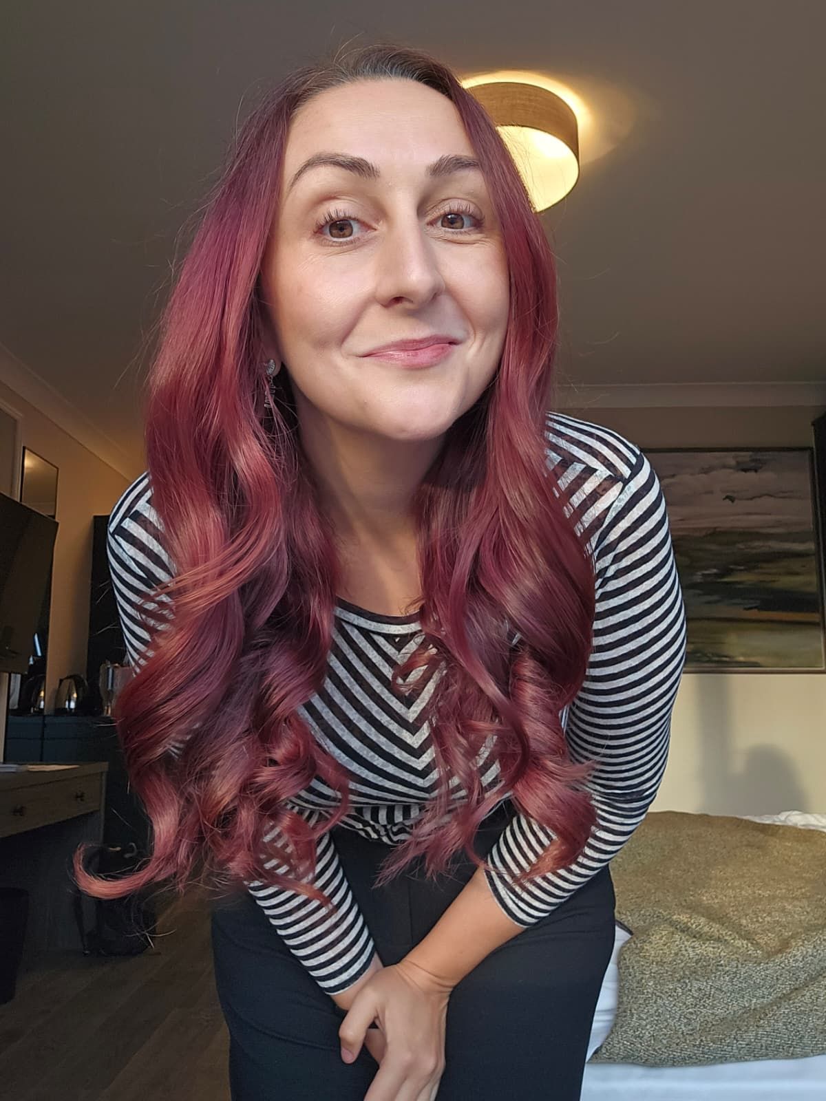 Katie leaning towards the camera, smiling, in a striped top