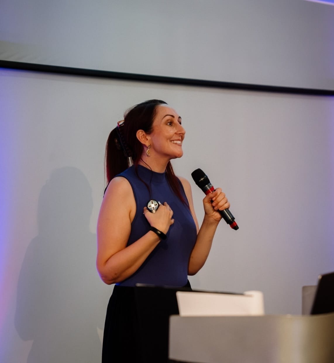 Katie Ford speaking on stage with a microphone
